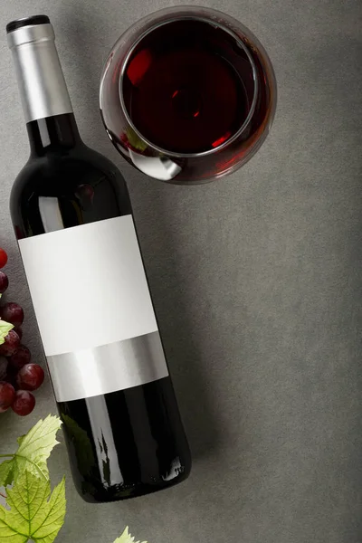 Bottle of red wine with label. Glass of wine and grape. Wine bottle mockup. Top view.