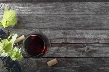 Kırmızı şarap ve üzüm. Şarap ve üzümler, ahşap bir masanın mantarlarıyla eski bir ortamda. Üst görünüm.