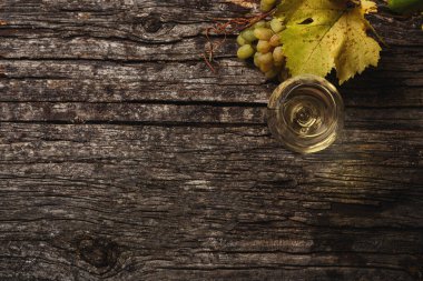 Bardakta beyaz şarap, masada üzüm ve üzüm dalları. Üst Manzara. Metin için boşluk kopyala.