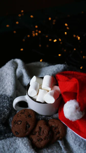 Becher mit heißer Schokolade mit Weihnachtsmütze, Marshmallow und Schokoladenkeksen — Stockfoto