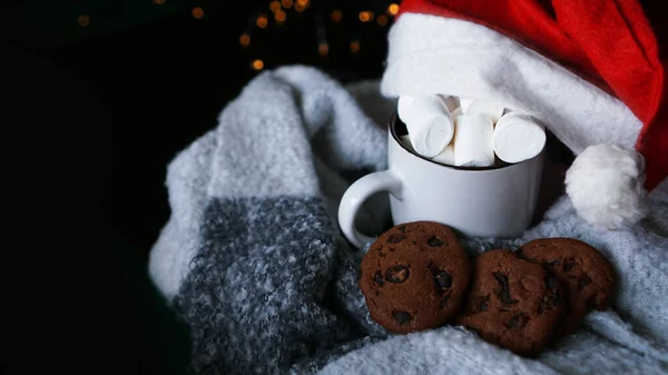 Becher mit heißer Schokolade mit Weihnachtsmütze, Marshmallow und Schokoladenkeksen — Stockfoto