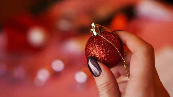 Mão feminina segura bola vermelha no fundo de Natal — Fotografia de Stock