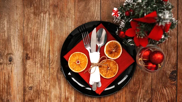 Christmas dinner decoration with dried oranges and a red napkin on a black plate — Stock Photo, Image