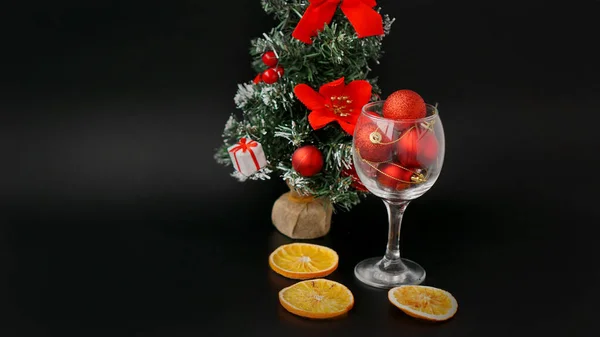 New Year tree on a black background. Red Christmas balls in a wine glass — Stock Photo, Image