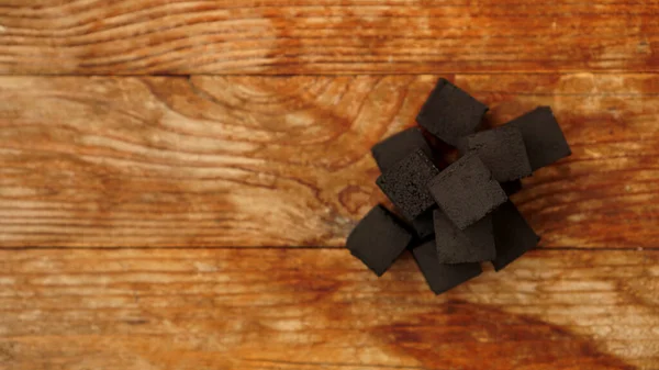 Cubos de carbón de coco para narguile sobre fondo de madera. — Foto de Stock