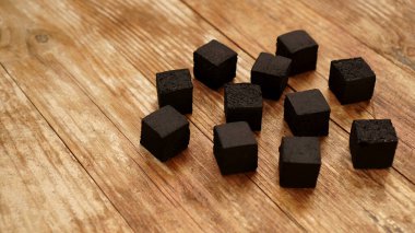 Tahta arka planda nargile için hindistan cevizi kömürü küpleri.