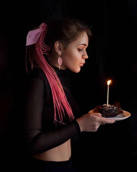 Ein schönes Mädchen mit rosa Afro- oder Zizi-Zöpfen mit einer Geburtstagstorte auf einem schwarzen — Stockfoto