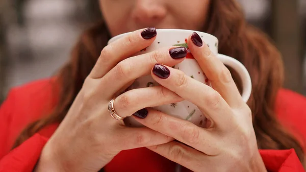 Mãos femininas segurando copo com bebida escura quente fora no dia de inverno — Fotografia de Stock