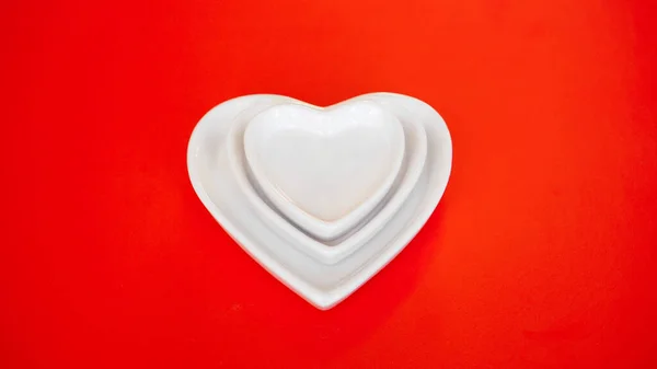 Srdce formulář bílé desky na červeném pozadí — Stock fotografie