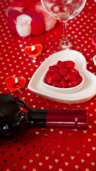 Valentines day. Bottle of vine, glasses, red roses, candles - red background — Stock Photo, Image