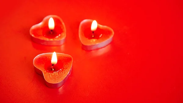 Three red burning candles with heart shaped decorations. St Valentines day. — Stock Photo, Image