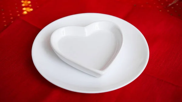Heart shaped white plate on red — Stock Photo, Image