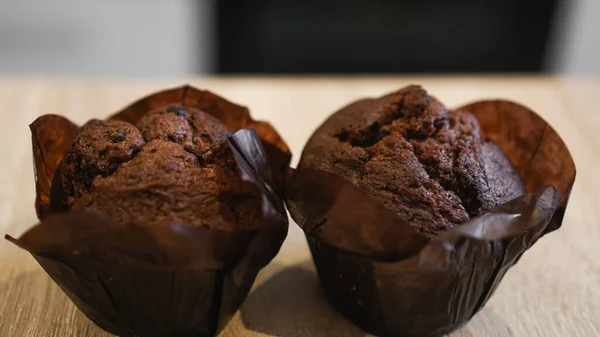 Dois muffins de chocolate em uma mesa de madeira contra a cozinha moderna — Fotografia de Stock