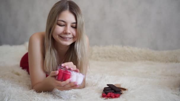 Cute uśmiechnięte młode kobiety otwierając prezent w białym pokoju — Wideo stockowe