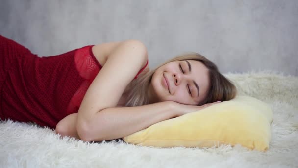 A beautiful girl smiles in her sleep. She lies on a yellow pillow — Stock Video