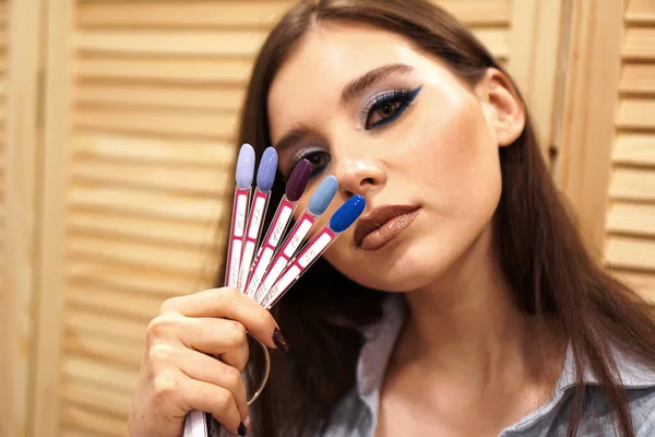 Gyönyörű lány kék smink takarja arcát egy paletta körmökkel — Stock Fotó