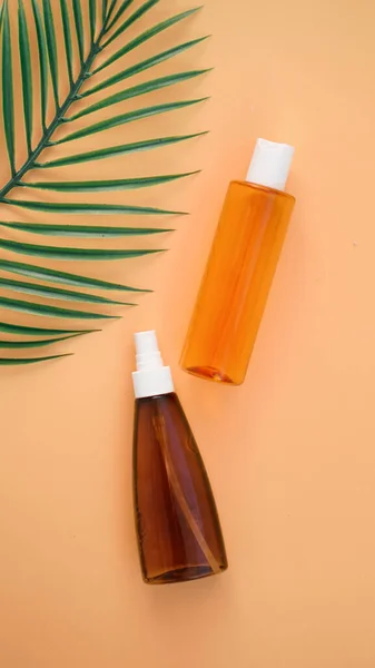 Suntan lotion bottle on background with tropical leaf. Top view with copy space