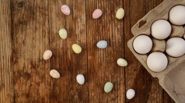Karton tepside tavuk yumurtası ve ahşap arka planda Paskalya dekoru.