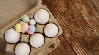 Karton tepside tavuk yumurtası ve ahşap bir arka planda Paskalya dekoru..