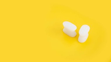 Sarı arka planda beyaz silikon parmak ayırıcı. Hallux valgus 'un önlenmesi ve tedavisi