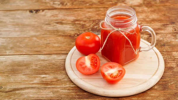 Glass of tomato juice on wooden table. Fresh tomato juice and chopped tomatoes