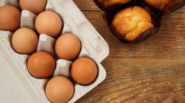 Yumurtalı tepsi ve kağıt formlarda lezzetli çörekler. Ahşap arka planda, yatay fotoğraf.
