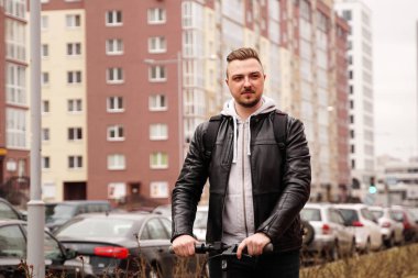 Şehirde elektrikli scooter kullanan modern bir adam.