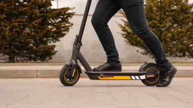 Elektrikli scooterla gezen genç bir adamın kırpılmış görüntüsü.