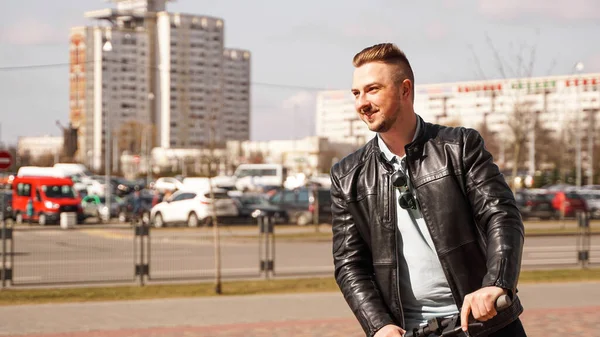Şehirde elektrikli scooter kullanan modern bir adam.