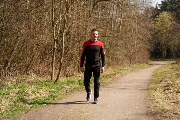 Een man in sportkleding op een bospad. Een man na een ochtend joggen loopt in het bos — Stockfoto