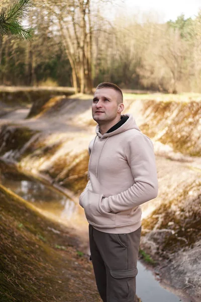 Een jonge man in een comfortabel pak loopt door het bos bij de rivier.. — Stockfoto