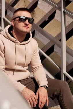 Genç bir adam şehrin basamaklarında oturuyor. Şehir tarzı. Yaşam tarzı fotoğrafı.