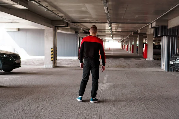 Um jovem de uniforme desportivo num estacionamento subterrâneo. — Fotografia de Stock
