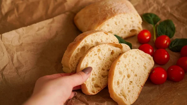 Ciabatta slices and cherry tomatoes on craft paper. — Stock Photo, Image