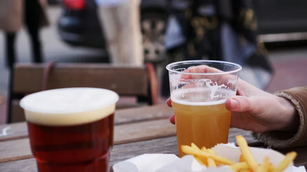 Girlfriends drink beer at the street food festival. French fries, unhealthy food