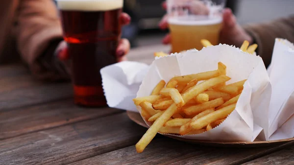 Girlfriends drink beer at the street food festival. French fries, unhealthy food