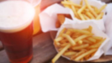 Tahta bir masada siyah bira ve patates kızartması. Yemek katı. Bulanık soyut arkaplan