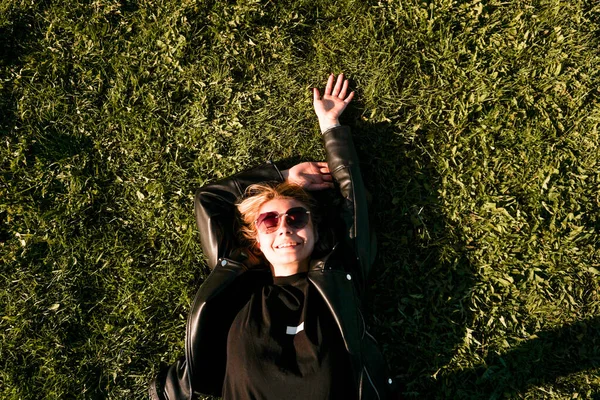 美しい健康的な若い女性が横になり、緑の芝生の上でリラックス — ストック写真