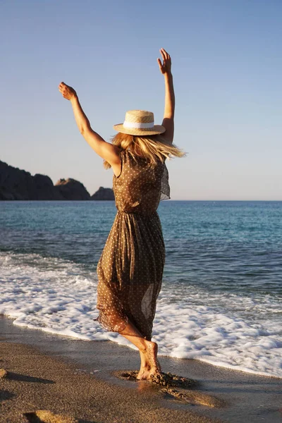 Женщина на пляже в коричневом платье и в соломенной шляпе. Отдых на пляже — стоковое фото