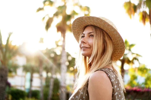 Ritratto di una giovane bionda in cappello su sfondo tropicale — Foto Stock