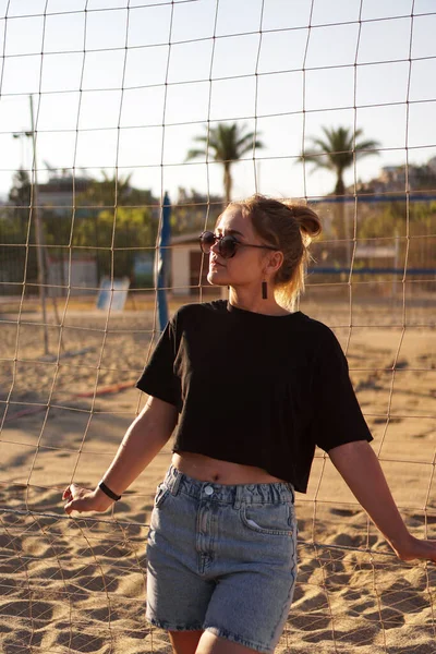 Retrato de mujer atractiva cerca de la red de voleibol en la playa. Foto vertical — Foto de Stock