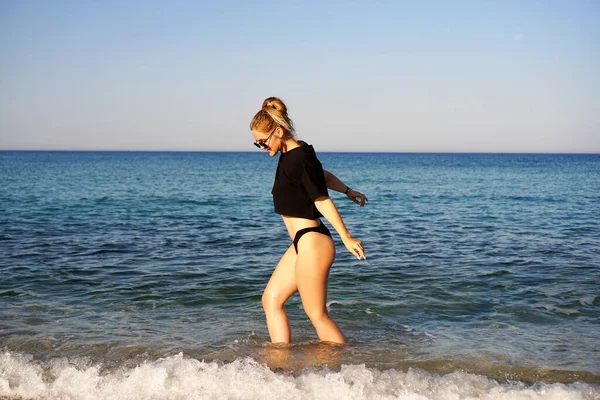 Молодая женщина в черной майке и трусах на морском пляже — стоковое фото