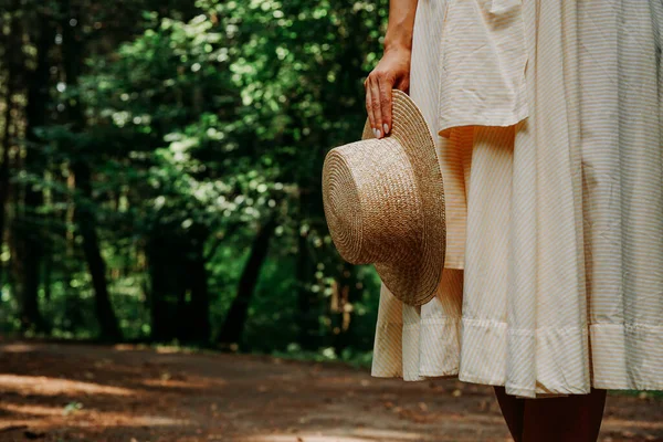 Foto in primo piano di una mano di donna che tiene un cappello di paglia sullo sfondo — Foto Stock