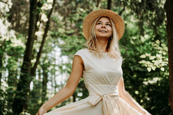 Junge Frau mit Strohhut hält den Saum ihres weißen Kleides — Stockfoto