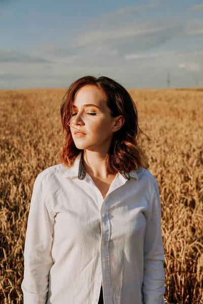 Портрет рыжеволосой девушки в белой рубашке. Она в поле в солнечный день — стоковое фото