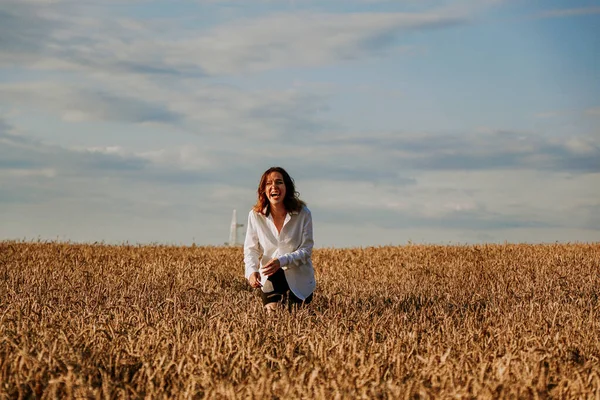 Mulher feliz corre em um campo de trigo em um dia de verão. Concepção de felicidade e alegria — Fotografia de Stock