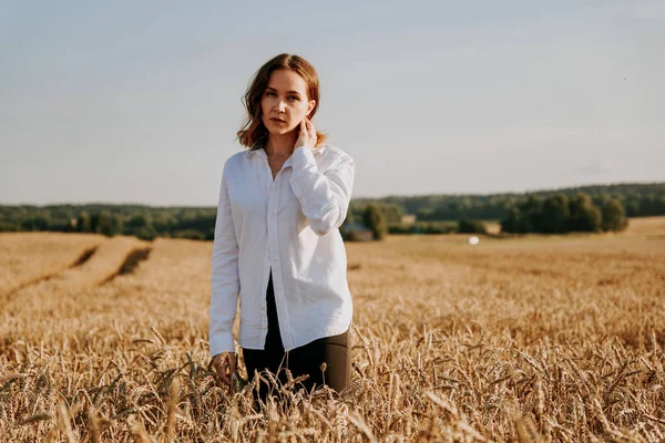 Retrato de menina ruiva em uma camisa branca. Ela no campo de centeio em um dia ensolarado — Fotografia de Stock
