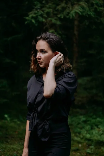 Jeune femme portrait serré dans une forêt sombre. Femme en chemise noire — Photo