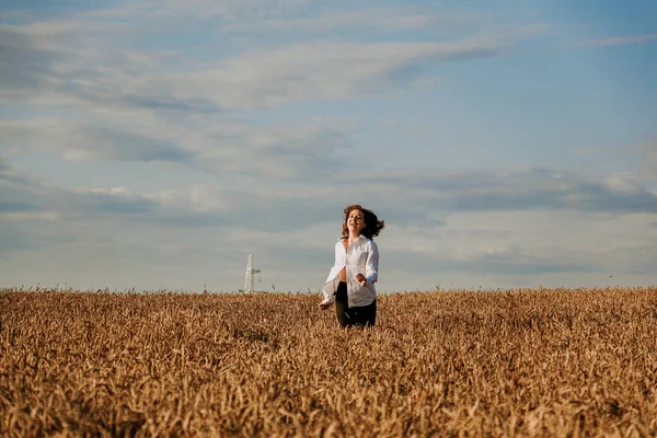 Mulher feliz corre em um campo de trigo em um dia de verão. Concepção de felicidade e alegria — Fotografia de Stock