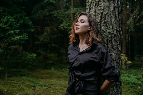 Jeune femme portrait serré dans une forêt sombre. Femme en chemise noire — Photo